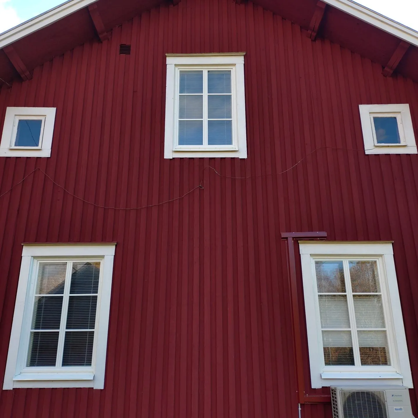 Röd trägavel med fönster i två luft och spröjs.